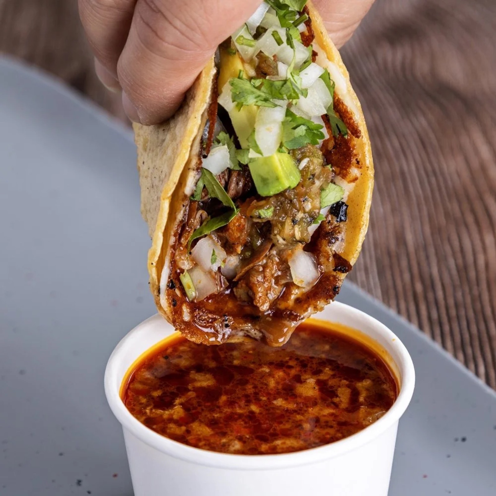 Birria taco from Spitfire being dipped into consomé.